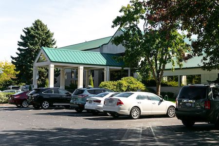 Facility parking lot with several cars parked in front of entrance.