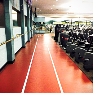3 lane red indoor running track surrounds a collection of exercise equipment.