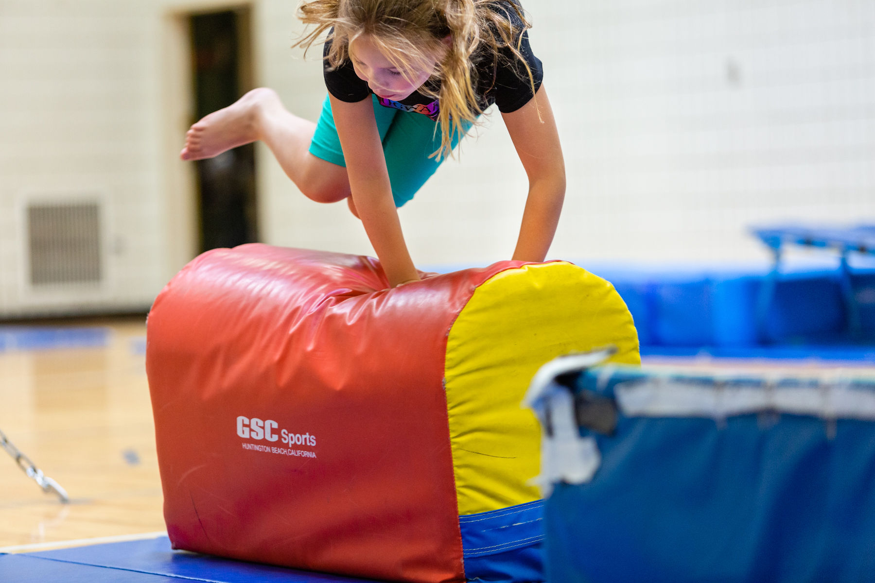 Active child jumping over colorful obstacle, while participating in Fit Kidz youth program.